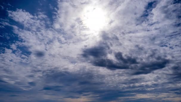 Schichtenwolken bewegen sich in blauem Himmel unter heller Sonne, flauschige Wolkenlandschaft im Zeitraffer — Stockvideo