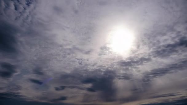 Gelaagde wolken bewegen in de blauwe lucht onder heldere zon, pluizig wolkendek Timelapse — Stockvideo