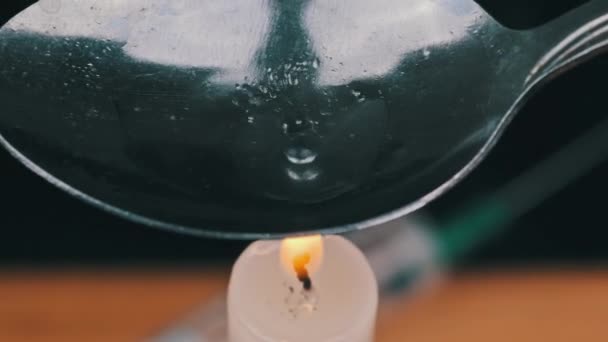 Příprava dávky heroinu v lžičce nad plamenem svíčky — Stock video