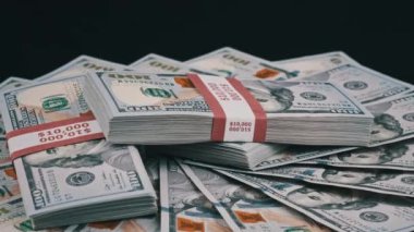 Para Yığını Üzerinde Yatan ve Siyah Arkaplanda Dönen Dolar Paketleri