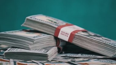 Para Yığını Üzerinde Yatan ve Mavi Arkaplanda Döndüren Dolar Paketleri