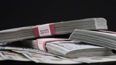 Para Yığını Üzerinde Yatan ve Siyah Arkaplanda Dönen Dolar Paketleri