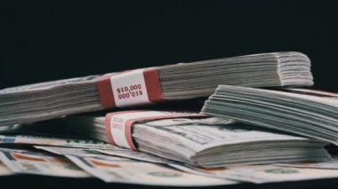 Para Yığını Üzerinde Yatan ve Siyah Arkaplanda Dönen Dolar Paketleri