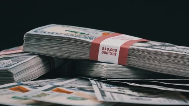 Пачки долларов лежат на груде денег и вращаются на черном фоне — стоковое видео