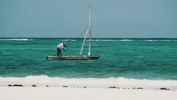 Africký rybář na staré suché dřevěné plachetnici v oceánu při přílivu, Zanzibar — Stock video