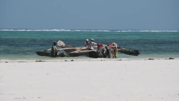 Skupina afrických rybářů v tradiční dřevěné lodi v blízkosti pláže, Zanzibar — Stock video