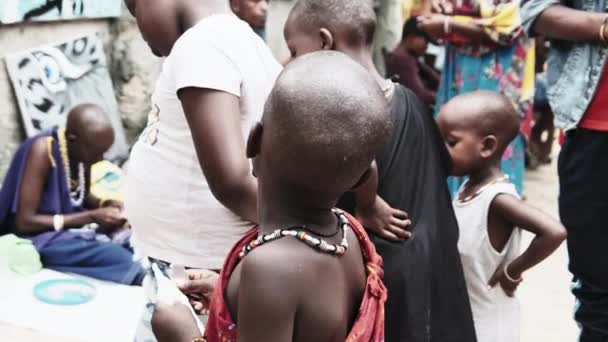 Lokale hongerige Afrikaanse kleine kinderen lopen op straat onder de mensen, Zanzibar — Stockvideo