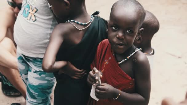 Lokale Afrikaanse hongerige kind eet papier op straat onder mensen, Zanzibar, Afrika — Stockvideo