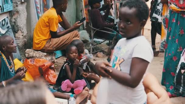 Местные голодные африканские маленькие дети прогуливаются по улице среди людей, Занзибар — стоковое видео