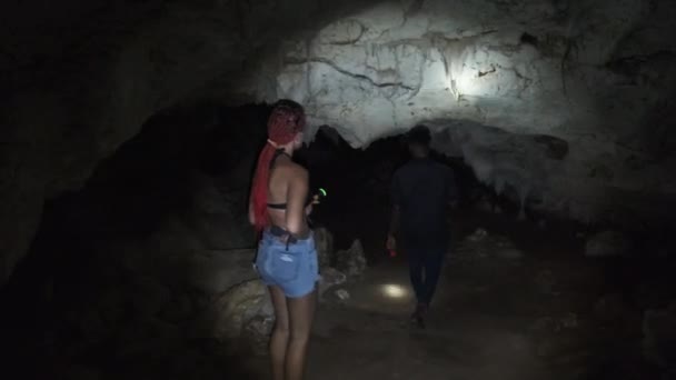 Woman Explores Stalactites Inside a Deep Dark Cave, Illuminating with Flashlight — Stock Video