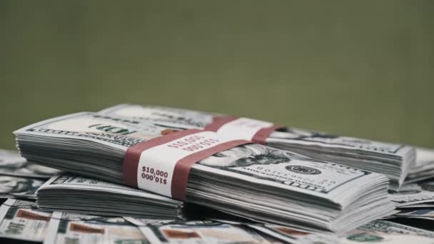 美元捆绑躺在一堆钱上，在绿色背景和金钱上旋转 — 图库视频影像
