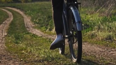 Woman on Bicycle Rides Along Forest Path in a Green Area on a Sunny Summer Day