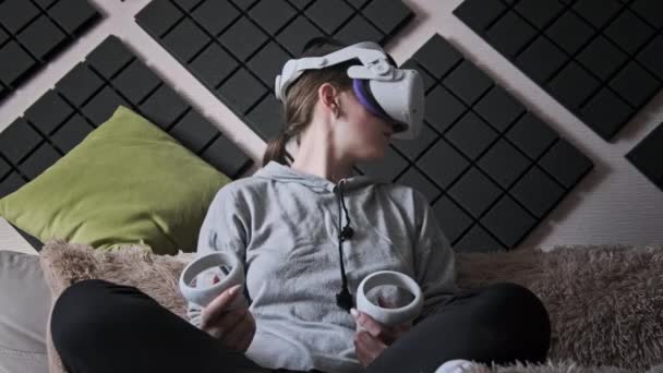 Młoda Kobieta Kasku Wirtualnej Rzeczywistości Siedząca Kanapie Poruszająca Joystickami Domu — Wideo stockowe