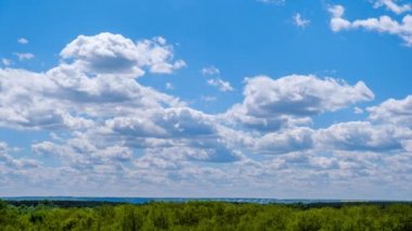 Kümülüs bulutlarının zaman çizelgesi yeşil ufukta mavi gökyüzünde hareket ediyor. Işık bulutları bulut uzayında şekillerini değiştirirler. Bulutların arka planı, zaman atlaması. Anlaşıldı uzay, hava, doğa. 4K
