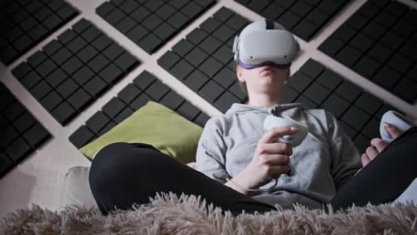 Młoda Kobieta Kasku Wirtualnej Rzeczywistości Siedząca Kanapie Poruszająca Joystickami Domu — Wideo stockowe