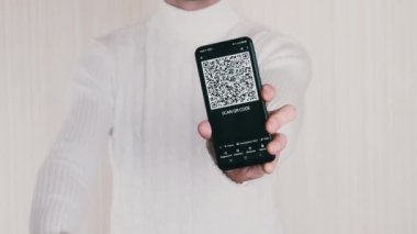 Adam akıllı telefonda QR kodu gösteriyor ve beyaz arkaplanda da onay işareti var. Cep telefonu ekranındaki yazı - QR kodunu tara. İzole et. Dijital para, kasa, ilaç, ödemeler. 4K