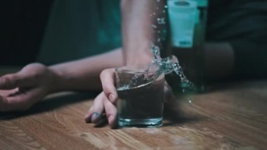 Bir alkoliğin Yavaş Hareketi yere düşer. Bir bardak alkolle, aşırı dozda votkayla. Sarhoş bir gencin eli şişenin yanına düştü. Yakın plan. Alkol bağımlılığı, alkolizm
