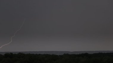 Fırtına bulutlarında şimşek çakıyor. Şiddetli bulutlar birden fazla şimşek ve fırtına patlaması getirir. Orman ufkunun üzerinde gece vakti büyük şimşekler çakar. Ağır çekim. 4K