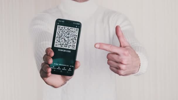 男性の手は白い背景にスマートフォンのQrコードを示しています 携帯電話の画面上の碑文 Qrコードをスキャンします 隔離されてる デジタル現金 Covid 支払い デジタル化の概念 — ストック動画