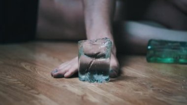 Bir alkoliğin Yavaş Hareketi yere düşer. Bir bardak alkolle, aşırı dozda votkayla. Sarhoş bir gencin eli şişenin yanına düştü. Yakın plan. Alkol bağımlılığı, alkolizm