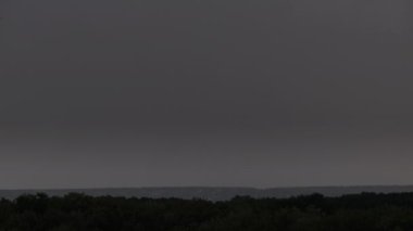 Fırtına bulutlarında şimşek çakıyor. Şiddetli bulutlar birden fazla şimşek ve fırtına patlaması getirir. Orman ufkunun üzerinde akşam vakti büyük yıldırımlar düşüyor. Ağır çekim. 4K