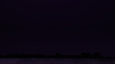 Gece gökyüzünde fırtınalı bulutlarda şimşekler çakıyor. Gece büyük bir şimşek çaktı. Şehir ufkunun üzerinde karanlık gökyüzü. Şiddetli bulutlar birden fazla şimşek ve fırtına patlaması getirir. Yavaş Hareket 4K