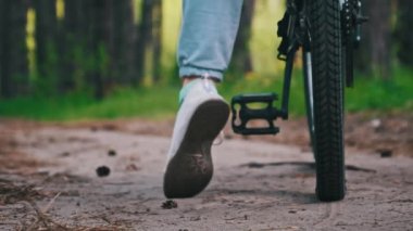 Kırsal bir parkta yeşil ağaçlar arasında bisiklet süren bir kadın. Bisikletli genç bir kadın yaz günü yol boyunca ağır çekimde bisiklet sürüyor. Spor yaşam tarzı, boş zaman aktivitesi, tatil
