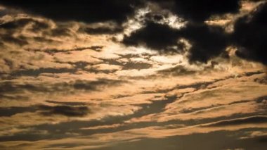 Katmanlı turuncu bulutlar gün batımında hareket eder. Bulutlar şekil değiştirir ve bulut uzayında çözünürler. Görkemli dramatik gökyüzü. Bulutlu zaman çizelgesi. Hava değişimi. Doğada şaşırtıcı renkler 4K