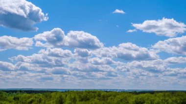 Kümülüs bulutlarının zaman çizelgesi yeşil ufukta mavi gökyüzünde hareket ediyor. Işık bulutları bulut uzayında şekillerini değiştirirler. Bulutların arka planı, zaman atlaması. Anlaşıldı uzay, hava, doğa. 4K