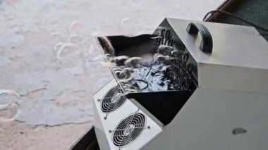 Çocukların tatilinde kullanılan otomatik sabun köpüğü üfleme makinesi. Sabun köpüğü jeneratörü açık hava festivalinde sabun köpüğü üretiyor. Yavaş çekim.