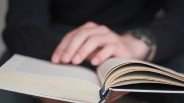 Genç adam kitap okuyor ve sayfaları çeviriyor, kapat, yavaş çekim. Erkek eller bir kitap tutuyor ve sayfaları çeviriyor. Tanımlanamayan bulanık bir adam metni inceliyor. Öğrenme, kendini eğitme. 4K
