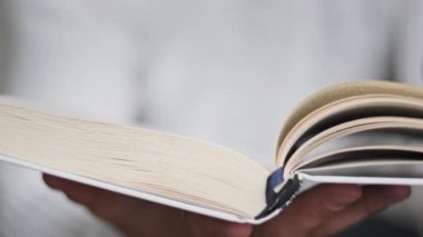 Genç adam kitap okuyor ve sayfaları çeviriyor, kapat, yavaş çekim. Erkek eller bir kitap tutuyor ve sayfaları çeviriyor. Tanımlanamayan bulanık bir adam metni inceliyor. Öğrenme, kendini eğitme. 4K
