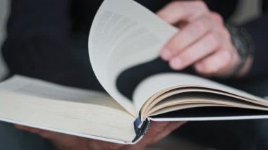 Kitap okumak ve sayfaları çevirmek, kapat. Genç adam bir kitap tutuyor ve sayfaları çeviriyor, ağır çekimde. Tanımlanamayan bir adam kitap okuyor ve sayfaları karıştırıyor. Kendi kendini eğitme