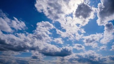 Katmanlı bulutların zaman akışı parlak güneşin altında mavi gökyüzünde ilerler. Cirrus bulutları şekil değiştirir ve bulut uzayında çözünür. Görkemli pofuduk gökyüzü. Bulutlu zaman çizelgesi. Hava değişimi. İnanılmaz doğa 4K