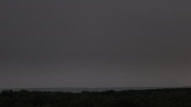 Fırtına bulutlarında şimşek çakıyor. Şiddetli bulutlar birden fazla şimşek ve fırtına patlaması getirir. Orman ufkunun üzerinde gece vakti büyük şimşekler çakar. Ağır çekim. 4K