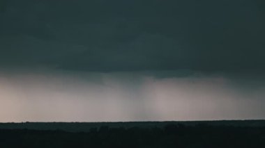 Fırtına bulutlarında şimşek çakıyor. Şiddetli bulutlar birden fazla şimşek ve fırtına patlaması getirir. Orman ufkunun üzerinde akşam vakti büyük yıldırımlar düşüyor. Ağır çekim. 4K