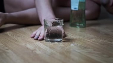 Bir alkoliğin Yavaş Hareketi yere düşer. Bir bardak alkolle, aşırı dozda votkayla. Sarhoş bir gencin eli şişenin yanına düştü. Yakın plan. Alkol bağımlılığı, alkolizm