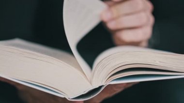 Genç adam kitap okuyor ve sayfaları çeviriyor, kapat, yavaş çekim. Erkek eller bir kitap tutuyor ve sayfaları çeviriyor. Tanımlanamayan bulanık bir adam metni inceliyor. Öğrenme, kendini eğitme. 4K