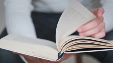 Genç adam kitap okuyor ve sayfaları çeviriyor, kapat, yavaş çekim. Erkek eller bir kitap tutuyor ve sayfaları çeviriyor. Tanımlanamayan bulanık bir adam metni inceliyor. Öğrenme, kendini eğitme. 4K