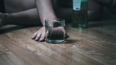 Bir alkoliğin Yavaş Hareketi yere düşer. Bir bardak alkolle, aşırı dozda votkayla. Sarhoş bir gencin eli şişenin yanına düştü. Yakın plan. Alkol bağımlılığı, alkolizm
