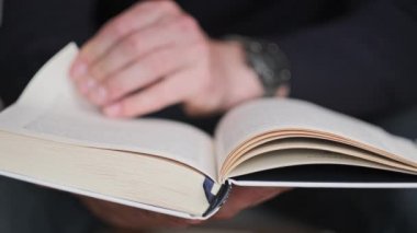Genç adam kitap okuyor ve sayfaları çeviriyor, kapat, yavaş çekim. Erkek eller bir kitap tutuyor ve sayfaları çeviriyor. Tanımlanamayan bulanık bir adam metni inceliyor. Öğrenme, kendini eğitme. 4K