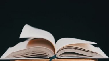 Beyaz kitabın sayfaları rüzgarın etkisiyle rastgele yer değiştiriyor. Kitabın sayfaları yavaş çekimde kendi kendine dönüyor, yakın çekimde. Stüdyoda siyah arka plan üzerine açık bir kitap