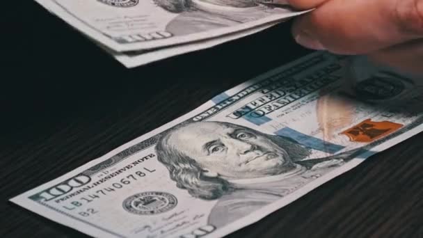 黒の木製のテーブルの上に新しい100ドル紙幣を数える 男性の手は紙幣 現金を数える 100ドル札を数える手のクローズアップ ビジネス 経済の概念 — ストック動画