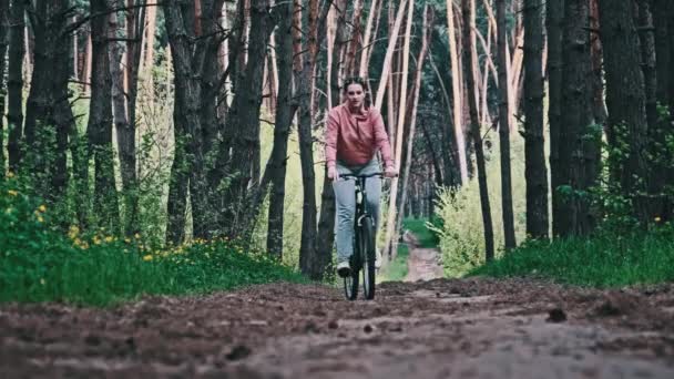 夏の日 スローモーションの森の道に沿って自転車に乗る若い女性 田舎の公園で緑の木の間の歩道を自転車に乗っている女性 スポーツライフスタイル レジャー活動 — ストック動画