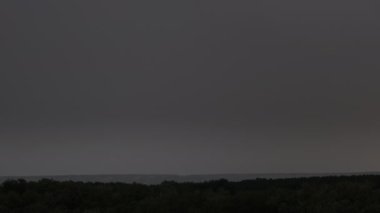 Fırtına bulutlarında şimşek çakıyor. Şiddetli bulutlar birden fazla şimşek ve fırtına patlaması getirir. Orman ufkunun üzerinde gece vakti büyük şimşekler çakar. Ağır çekim. 4K