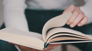 Kitap okumak ve sayfaları çevirmek, kapat. Genç adam bir kitap tutuyor ve sayfaları çeviriyor, ağır çekimde. Tanımlanamayan bir adam kitap okuyor ve sayfaları karıştırıyor. Kendi kendini eğitme