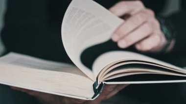 Kitap okumak ve sayfaları çevirmek, kapat. Genç adam bir kitap tutuyor ve sayfaları çeviriyor, ağır çekimde. Tanımlanamayan bir adam kitap okuyor ve sayfaları karıştırıyor. Kendi kendini eğitme