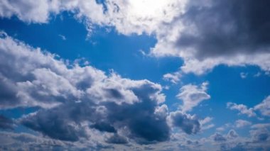 Katmanlı bulutların zaman akışı parlak güneşin altında mavi gökyüzünde ilerler. Cirrus bulutları şekil değiştirir ve bulut uzayında çözünür. Görkemli pofuduk gökyüzü. Bulutlu zaman çizelgesi. Hava değişimi. İnanılmaz doğa 4K