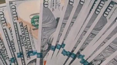 Erkek eller, yeşil doğanın arka planına karşı bir yelpaze gibi yeni dolarları gösteriyor. Genç adam elinde bir sürü 100 dolarlık banknot tutuyor. Açık hava banknotları yığını. Kâr kavramı, kağıt para biriktirme