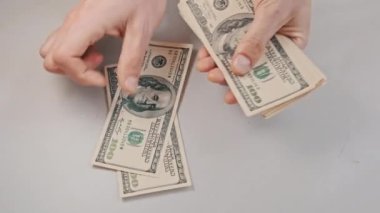 Beyaz bir masada eski 100 dolarlık banknotları saymak. Erkek eller kağıt para sayıyor, ev parası. 100 dolarlık banknotlar sayan bir elin yakın çekimi. İş, finans, ekonomi kavramı.